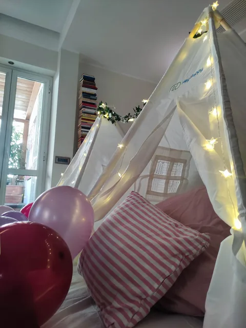 Dettaglio di una tenda TipiTime con lucine e cuscini rosa coordinati