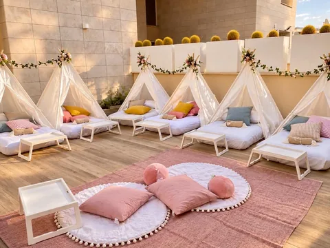 Allestimento TipiTime all'aperto con sei tende teepee bianche e cuscini rosa